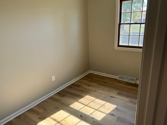 spare room with visible vents, baseboards, and wood finished floors