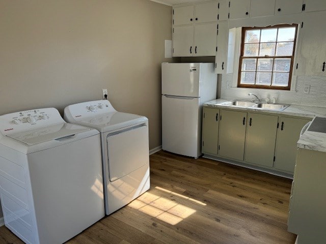 laundry room with washer and dryer, laundry area, a sink, and wood finished floors