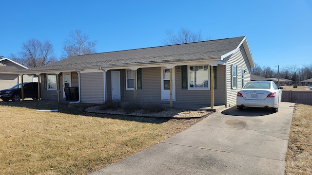 view of front of house featuring driveway, a front lawn, roof with shingles, and fence