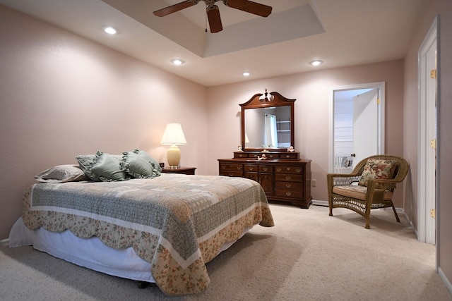 bedroom featuring a raised ceiling, ceiling fan, and light colored carpet