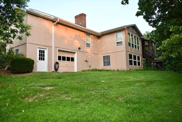 rear view of house with a garage and a lawn