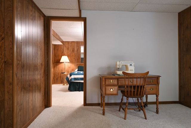 carpeted office featuring a drop ceiling and wooden walls