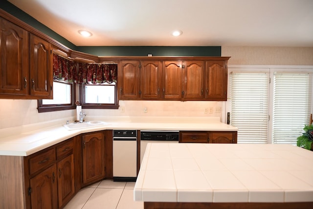 kitchen featuring dishwasher, light tile patterned floors, tile countertops, and sink