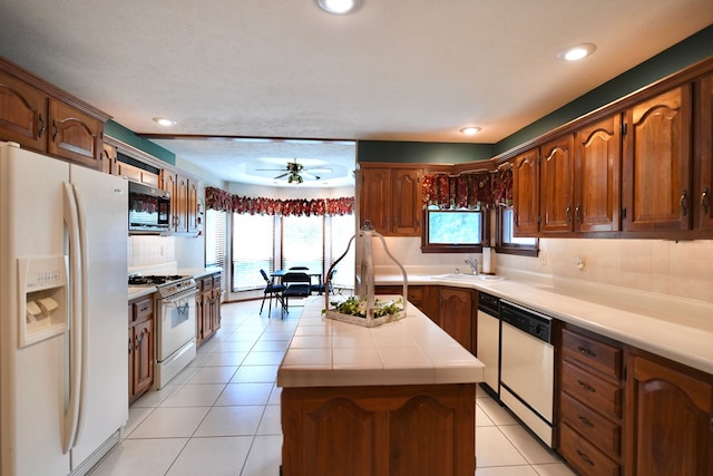 kitchen featuring backsplash, ceiling fan, a center island, and white appliances