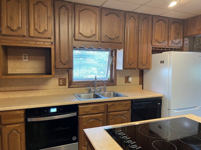 kitchen with a drop ceiling, stainless steel oven, white refrigerator, sink, and black dishwasher