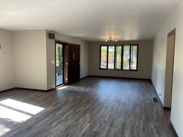 empty room featuring a notable chandelier and dark hardwood / wood-style floors