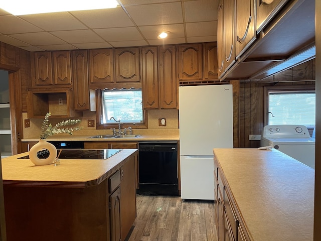 kitchen with sink, a center island, black appliances, and washer / dryer