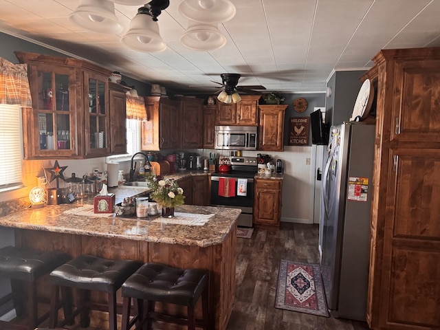 kitchen with stainless steel appliances, dark wood-type flooring, glass insert cabinets, a sink, and a peninsula