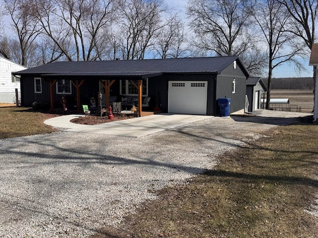 view of front of home with gravel driveway, an attached garage, and metal roof