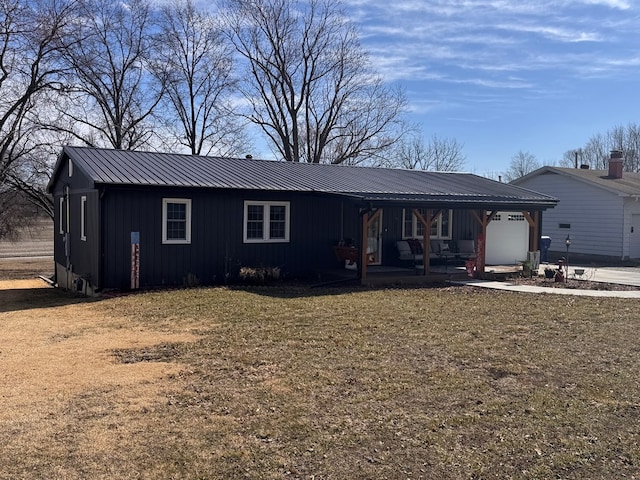 ranch-style house featuring a garage, a front lawn, metal roof, and board and batten siding