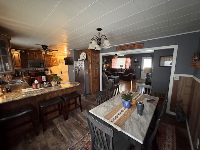 dining room featuring dark wood finished floors and ceiling fan with notable chandelier