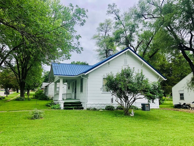 exterior space with metal roof, central AC, a porch, and a front yard