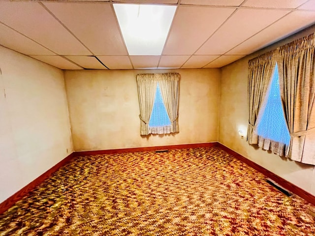 unfurnished room with a drop ceiling, carpet flooring, visible vents, and baseboards