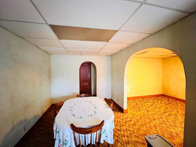 interior space with arched walkways, carpet flooring, a paneled ceiling, and baseboards