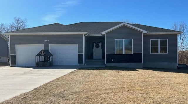 single story home with a garage, concrete driveway, a front lawn, and a shingled roof