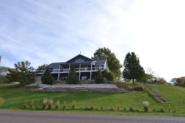 back of house featuring a lawn and a balcony