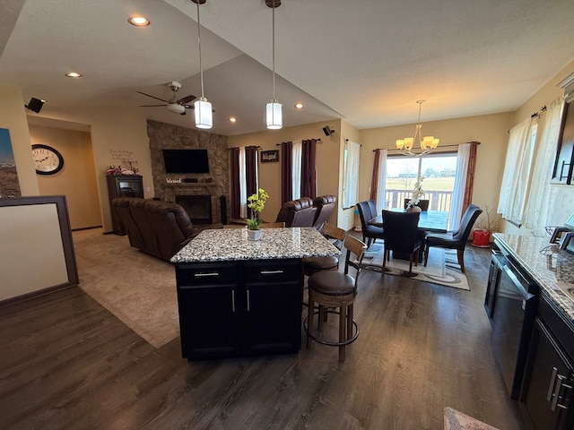 kitchen with open floor plan, dishwashing machine, ceiling fan with notable chandelier, a fireplace, and dark cabinetry