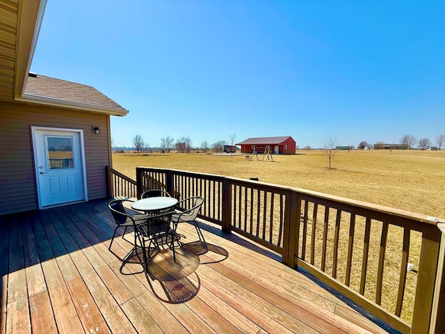 wooden terrace with a rural view, a lawn, and an outdoor structure