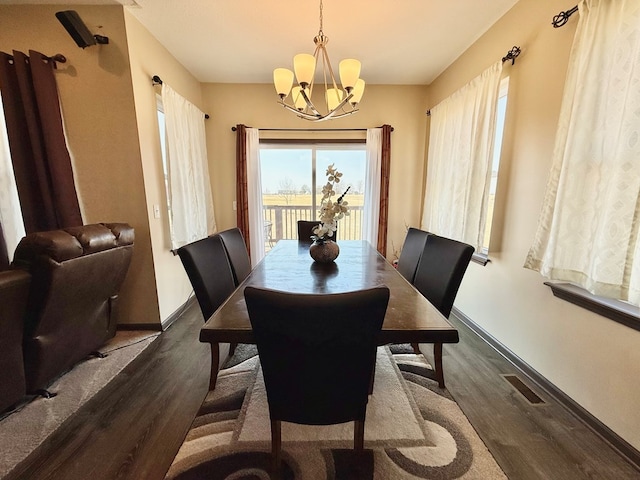 dining area with baseboards, wood finished floors, and a chandelier