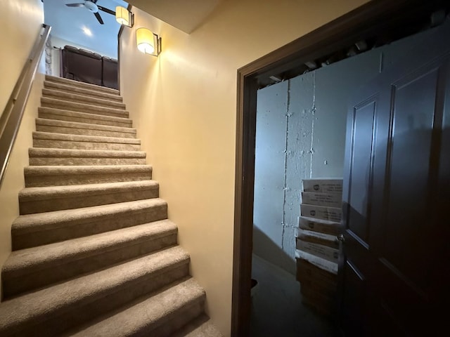 stairway featuring a ceiling fan