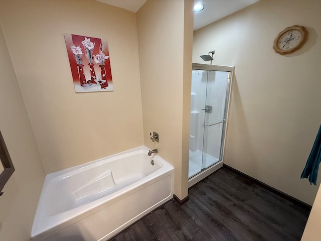 bathroom featuring baseboards, wood finished floors, a stall shower, and a bath