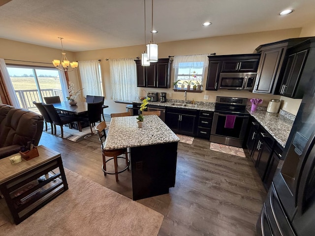 kitchen with a kitchen island, dark wood finished floors, a breakfast bar area, stainless steel appliances, and a sink