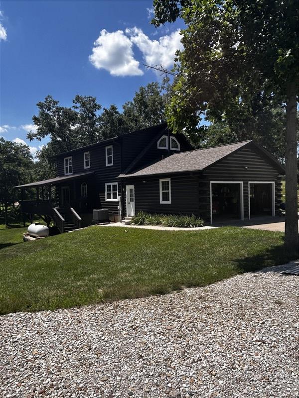 28730 State Highway T, Excello, MO 65247 - view of front of home featuring a garage, a front lawn, driveway, and roof with shingles
