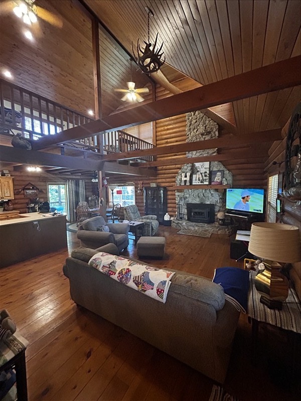 28730 State Highway T, Excello, MO 65247 - living room featuring hardwood / wood-style flooring, a stone fireplace, a wooden ceiling with exposed beams, a ceiling fan, and high vaulted ceiling