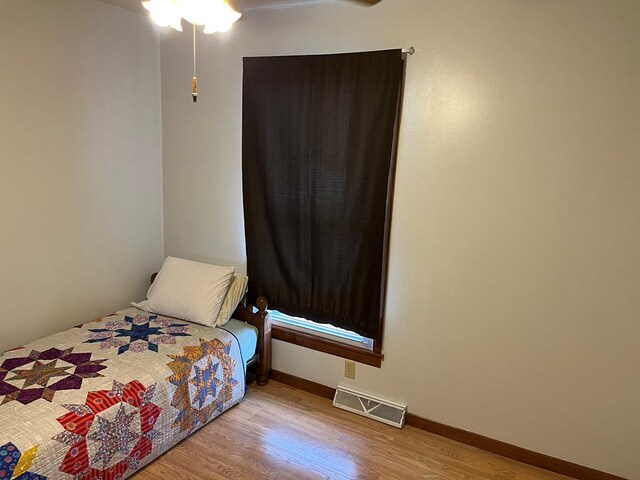 bedroom featuring a ceiling fan, wood finished floors, visible vents, and baseboards