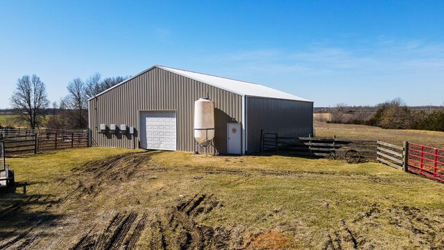 view of pole building featuring a rural view, a lawn, and fence