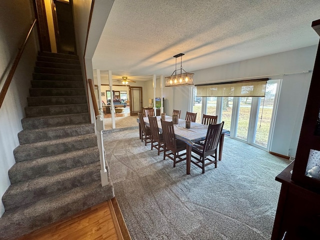 carpeted dining area with stairway, ceiling fan with notable chandelier, and a textured ceiling