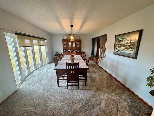 dining space featuring stairway, a textured ceiling, baseboards, and carpet floors