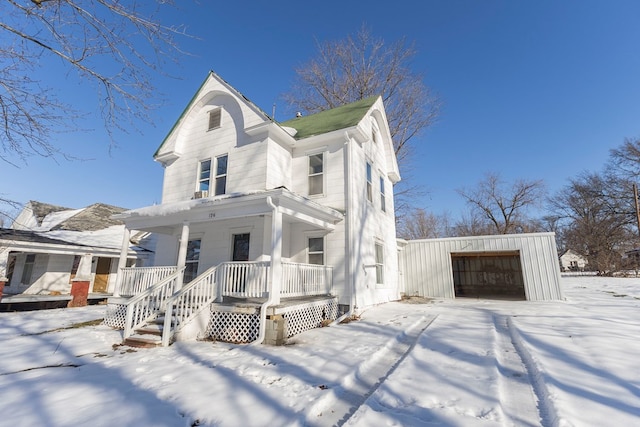 view of front facade featuring a garage, a porch, and an outbuilding