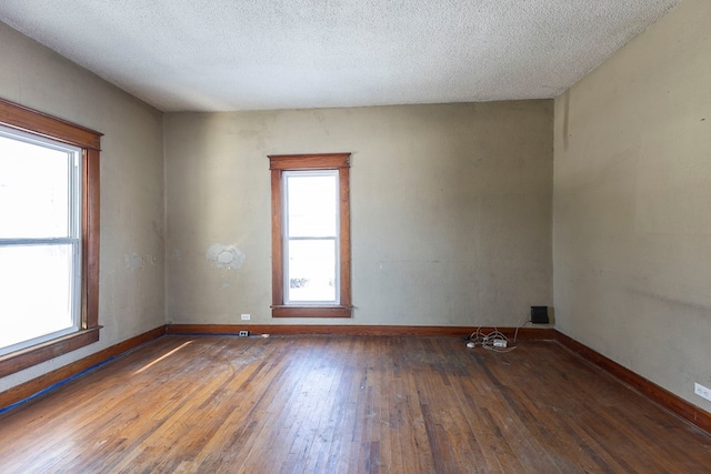 empty room featuring a textured ceiling and dark hardwood / wood-style flooring