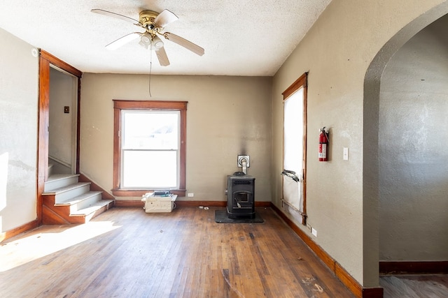 interior space featuring ceiling fan, a wood stove, a wealth of natural light, and dark hardwood / wood-style floors