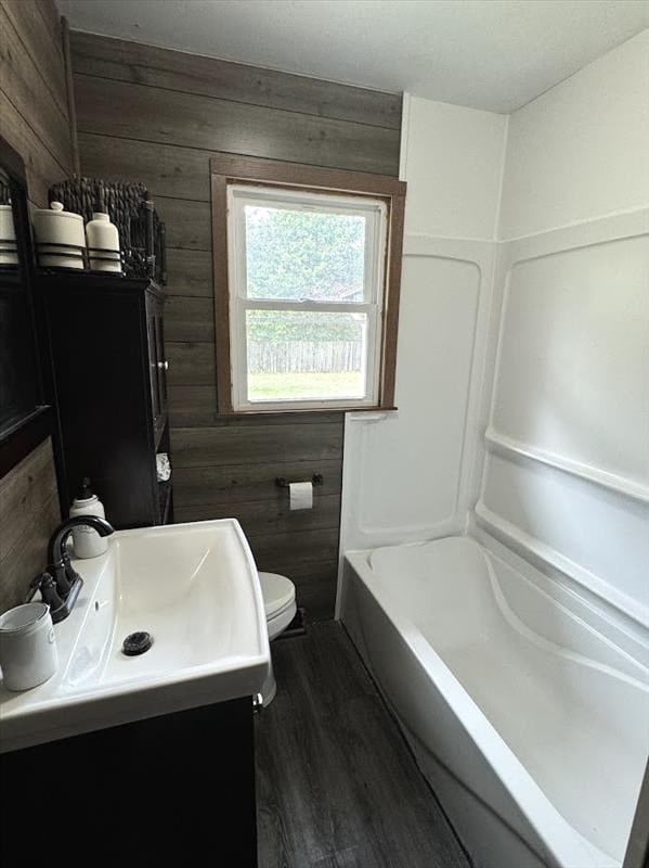 bathroom with hardwood / wood-style floors, vanity, toilet, and wooden walls