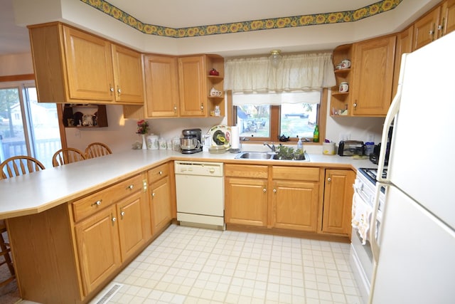 kitchen with a kitchen bar, kitchen peninsula, sink, and white appliances