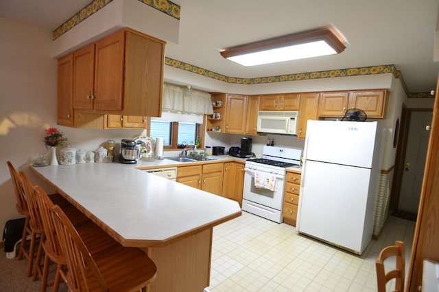 kitchen with a kitchen bar, kitchen peninsula, sink, and white appliances