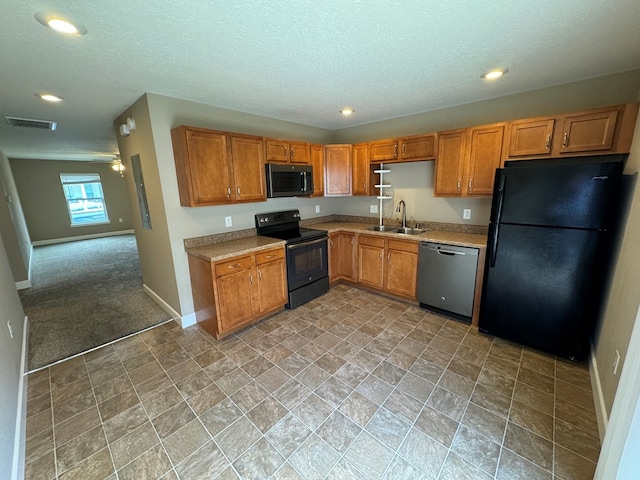 kitchen featuring light carpet, sink, black appliances, and a textured ceiling