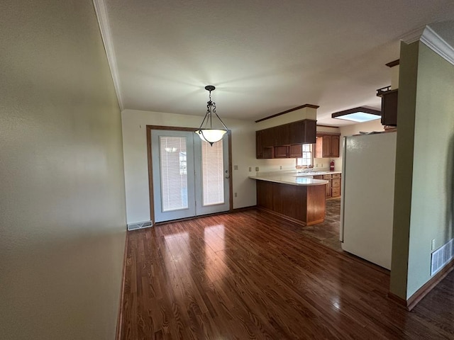 kitchen with kitchen peninsula, crown molding, dark hardwood / wood-style floors, and white fridge