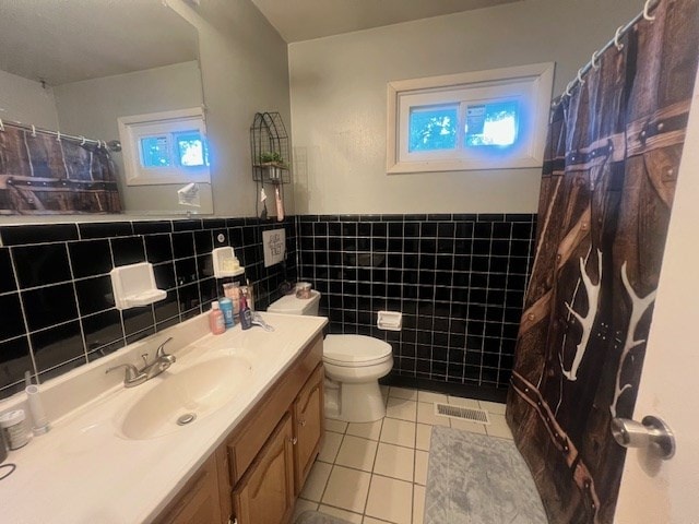 bathroom featuring tile patterned floors, vanity, tile walls, and toilet