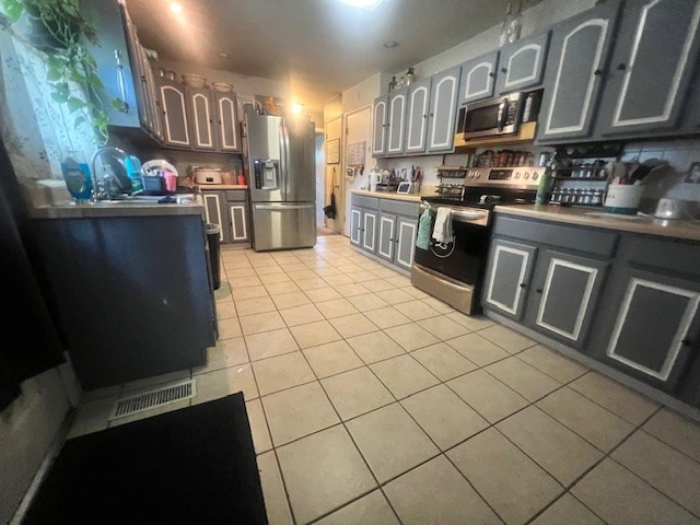 kitchen featuring appliances with stainless steel finishes, light tile patterned floors, and sink