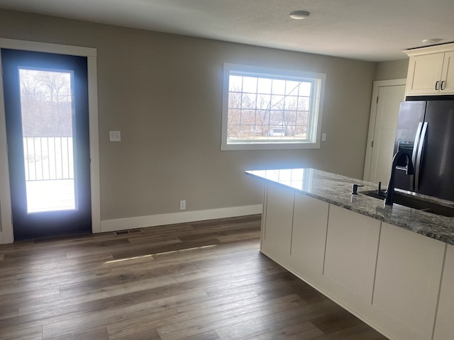 kitchen with sink, white cabinetry, light stone counters, a wealth of natural light, and stainless steel fridge with ice dispenser