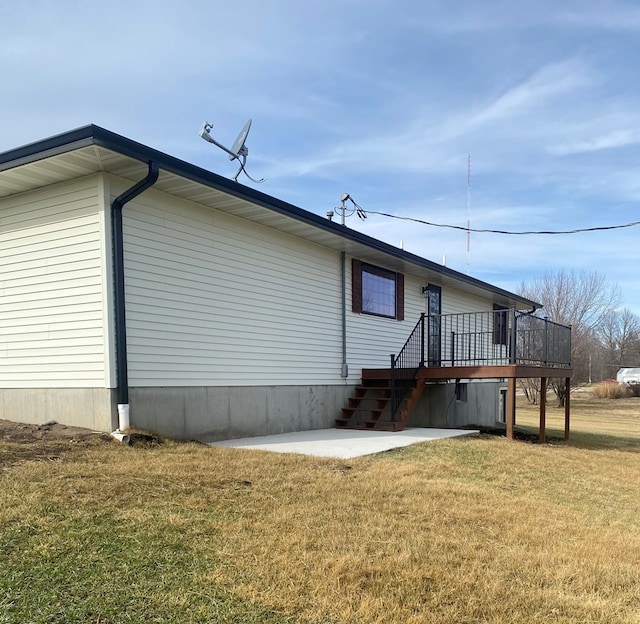 rear view of house featuring a wooden deck, a patio, and a lawn