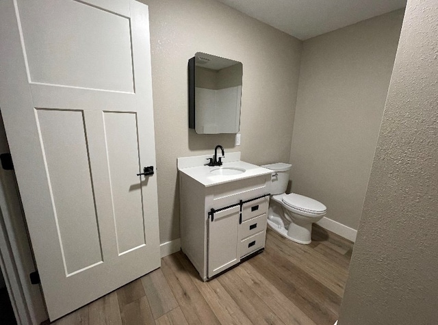 bathroom featuring vanity, hardwood / wood-style floors, and toilet