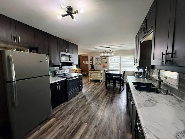 1205 Randolph St, Kirksville, MO 63501 - kitchen with stainless steel appliances, a chandelier, dark wood finished floors, light stone countertops, and hanging light fixtures