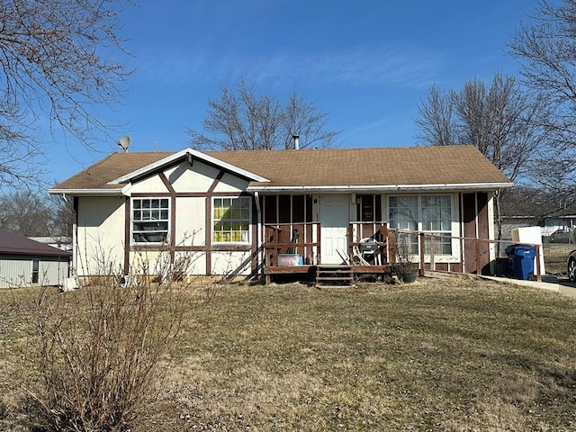 view of front of home with roof with shingles, covered porch, stucco siding, and a front lawn