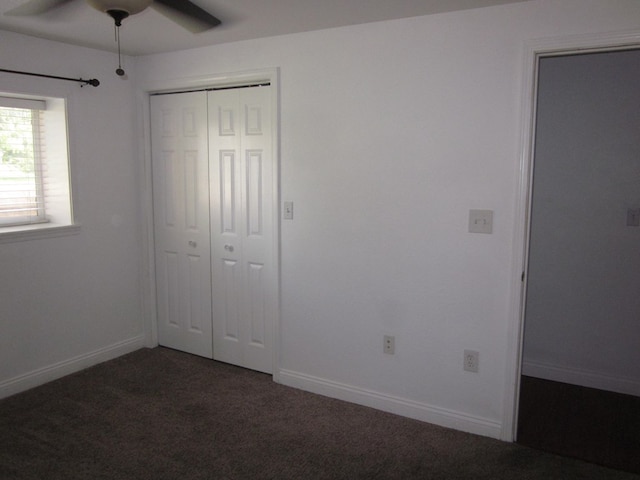 unfurnished bedroom with ceiling fan, a closet, and dark colored carpet