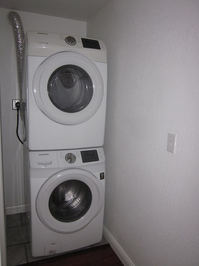 laundry area with stacked washer and dryer and dark wood-type flooring