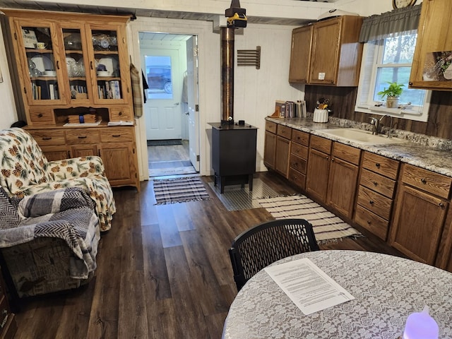 kitchen with dark hardwood / wood-style flooring, light stone counters, brick wall, sink, and wood walls